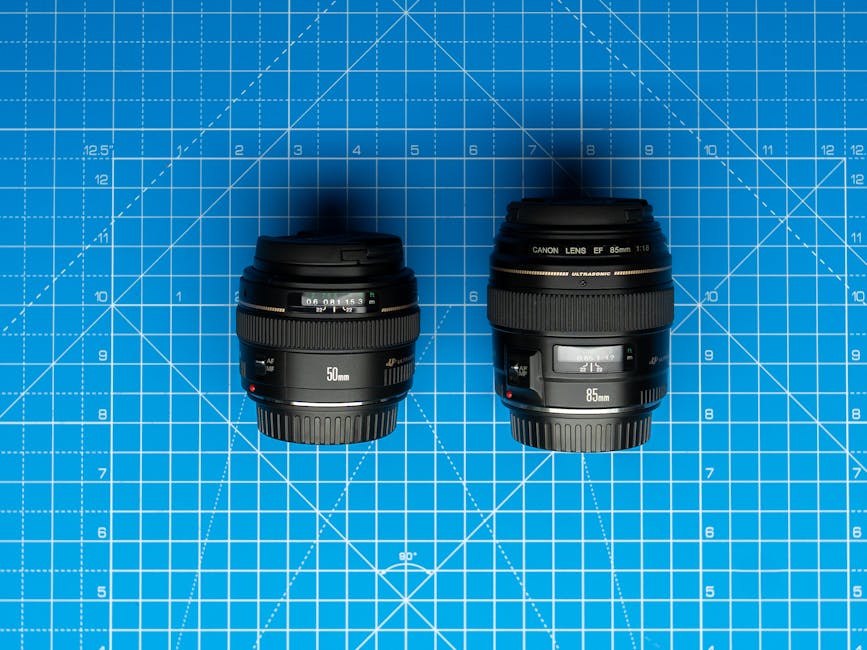 Two camera lenses placed on a blue graphing board with grid lines.